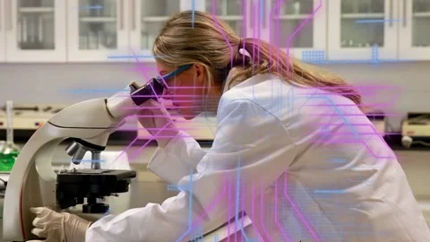 Lab researcher leaning and adjusting microscope focus, creating overlays for 库存影片 335235872