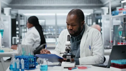 Lab researcher looking through scientific microscope lens to study cells Stock Footage 327418450
