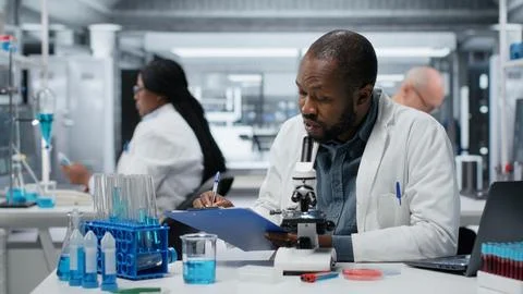 Lab researcher looking through scientific microscope lens to study cells Stock Photos