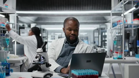 Lab researcher using laptop software to evaluate compound solutions Stock Footage 326011945