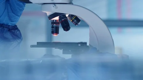 Lab Scientist in Protective Uniform Using Optical Microscope Stock Footage 128862988
