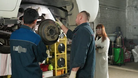 Lab Scientists Observing Mechanic and Taking Notes in Automotive Workshop Stock Footage 302195657