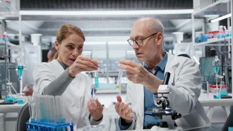 Lab team leader teaching intern to analyze liquid polymer properties Stock Footage 326831523