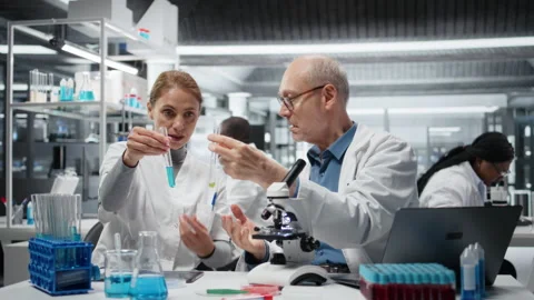 Lab team leader teaching intern to analyze liquid polymer properties Stock Footage 327244998