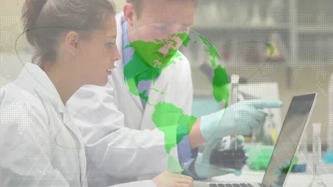 Lab team, one tilting flask as other comparing sample with laptop data, globe Stock Footage 328446607
