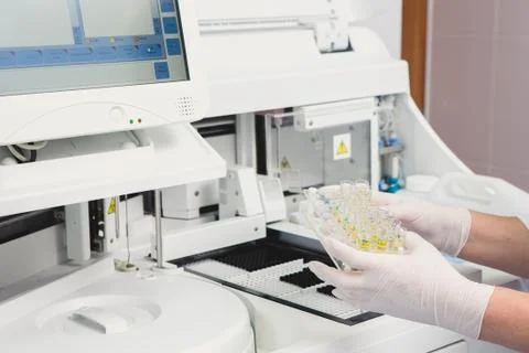 Lab tech loading samples into a chemistry analyzer Fotos Stock