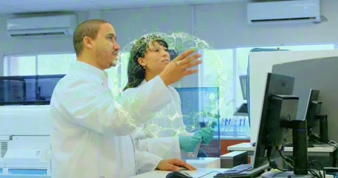 Lab tech operating mouse and scientist pointing tablet forming green holographic Stock Footage 317608173