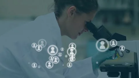 Lab tech peering microscope adjusting slide and causing user icons showing data 動画素材 332296523