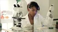 Lab tech using a pipette and other looking in microscope HD Footage