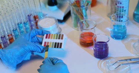Lab technician experiments mixing different solutions and using colored test Stock Footage 283662674