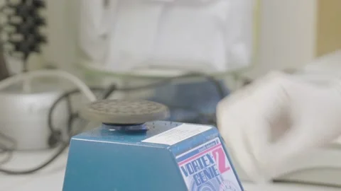 Lab technician hand with white glove puts test tube on vortex mixer base Stock Footage 169945359