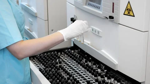 Lab technician loading test tubes into automated diagnostic analyzer. 스톡 동영상 347779601