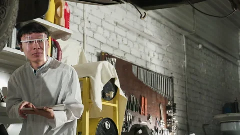 Lab Technician Observing Lifted Car for Technical Analysis in Workshop Stock Footage 304973397
