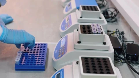 A lab technician places test tubes of liquid on a DNA analyzer Stock Footage 311106244