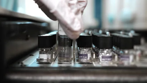 Lab technician placing sample into analyzer for automated diagnostic testing. Vídeos de archivo 347777825