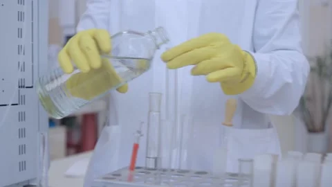 A lab technician pours a chemical into a test tube. Stock Footage 101980136