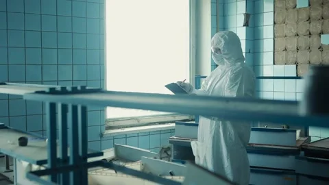 Lab technician in a protective suit and goggles stands at the laboratory window Stock Footage 131517802