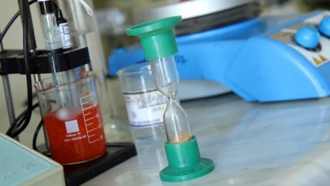 Lab technician puts an hourglass to count down time. Stock Footage 127321408