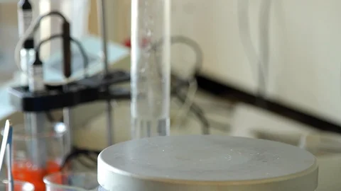 Lab technician puts a vessel with red substance on a magnet. 스톡 동영상 127321485