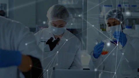 Lab technicians comparing liquids examining samples via microscope typing data Stock Footage 312771530