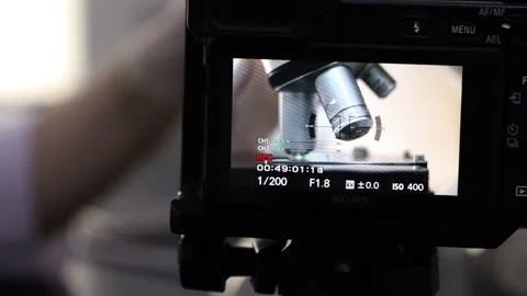 A lab technician's hand translates the lenses of a microscope Stock Footage 283793382