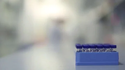 Lab Technicians Moving Behind Block of Vials Stock Footage 69087669
