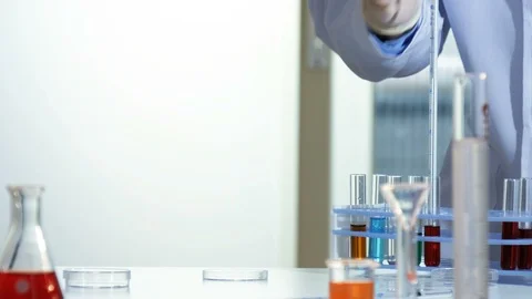 Lab worker adds a few drops of a red chemical from a pipette to a petri dish Stock Footage 88379014
