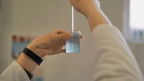 Lab worker hands doing laboratory testing with chemical liquid in beaker.  Stock Footage 128456235