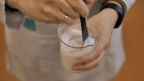 Lab worker hands mixing creamy substance in a measuring cup. Stock Footage 128456569