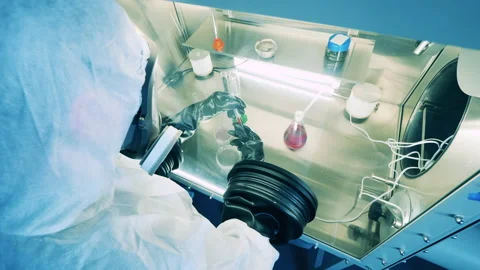 Lab worker in a hazmat suit is operating a laboratory cabinet Stock Footage 149695228