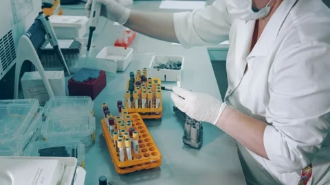 A lab worker holds a pipette dispenser and transfers blood samples from Covid 19 Stock Footage