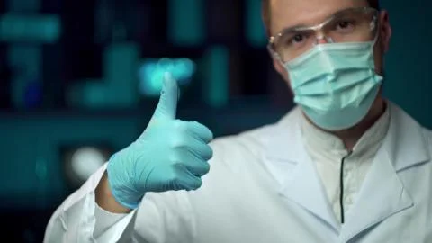 A lab worker in a mask puts on protective work glasses for working in Foto stock