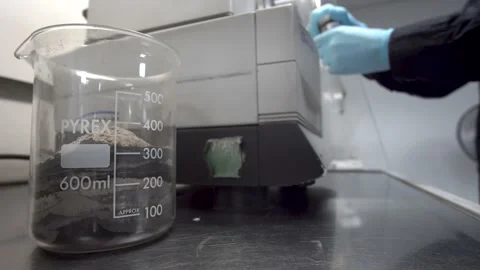 Lab worker prepares ore sediment sample for analysis with glass beaker Video stock 201530969