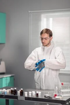 Lab worker putting on blue sterilized medical gloves to do some tests Stock Photos