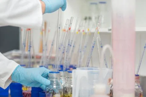 Lab worker taking dye from beaker using long pipette 스톡 사진