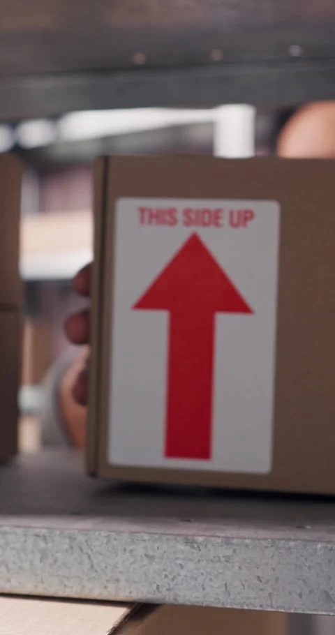 Label, arrow and person with box on shelf in storage depot for delivery Stock Footage 332039573