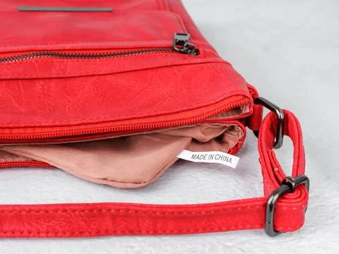 Label Made in China inside of a small red casual handbag with a long handle. Foto stock