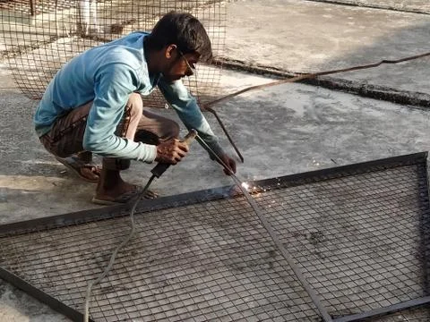 Labor is busy in making joints between iron girders by welding them together. Stock Photos