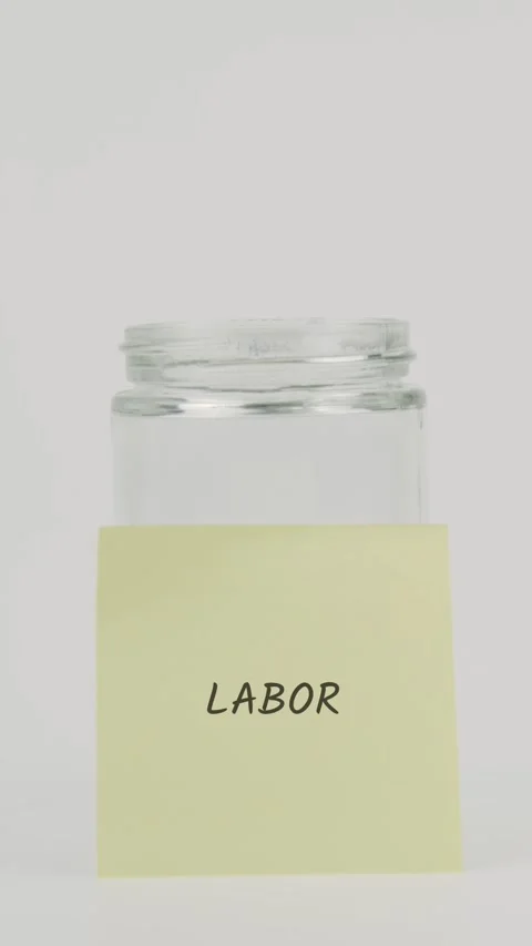 Labor text or word on yellow sticky note attached to glass jar with hand Stock Footage 311749598