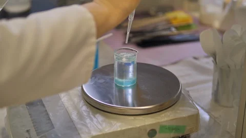 Laboratory assistant adds clear liquid to the tube with blue residuas.  Stock Footage 128455917
