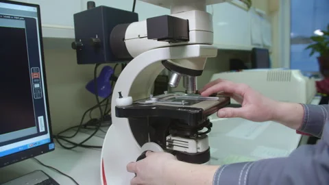 Laboratory assistant examines product under microscope Stock Footage 230036683