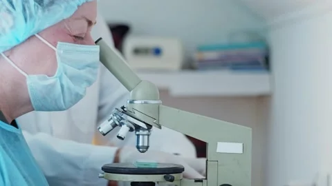 The laboratory assistant examines the samples in the eyepiece of the microscope. Stock Footage 172143884