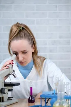 The laboratory assistant examines samples of materials under a microscope. Sc Stock Photos