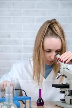 The laboratory assistant examines samples of materials under a microscope. Sc Stock Photos