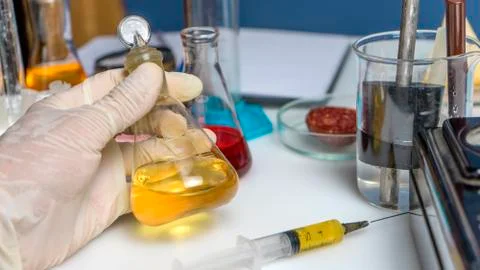 Laboratory assistant hand holds flask, test tubes and laboratory equipment. F Stock Photos