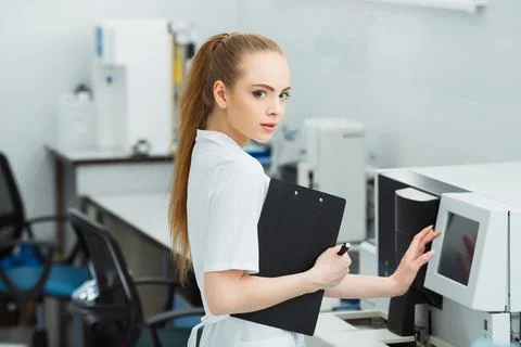 Laboratory assistant loading sample tubes for coagulation test analysis and Stock Photos