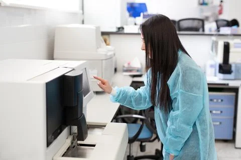 Laboratory assistant loading sample tubes for coagulation test analysis and Stock Photos
