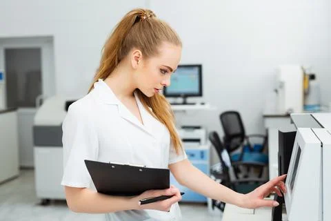Laboratory assistant loading sample tubes for coagulation test analysis and Stock Photos