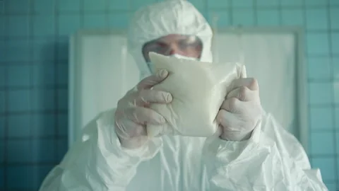 The laboratory assistant in a protective suit and glasses holds in his hands Stock Footage 131375654