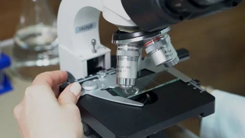 The laboratory assistant puts the glass with the material, turns on the lighting Stock Footage 231032635